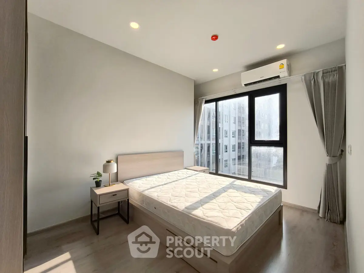 Modern bedroom with large window and natural light in urban apartment