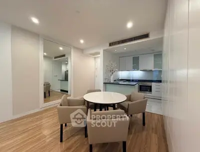 Modern dining area with elegant table and chairs, adjacent to a sleek kitchen with contemporary design.