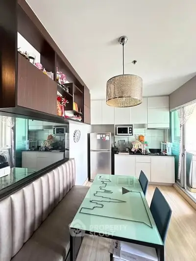 Modern kitchen with sleek design, featuring glass dining table and stainless steel appliances.