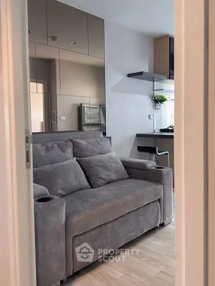 Modern living room with sleek gray sofa and stylish kitchen area.