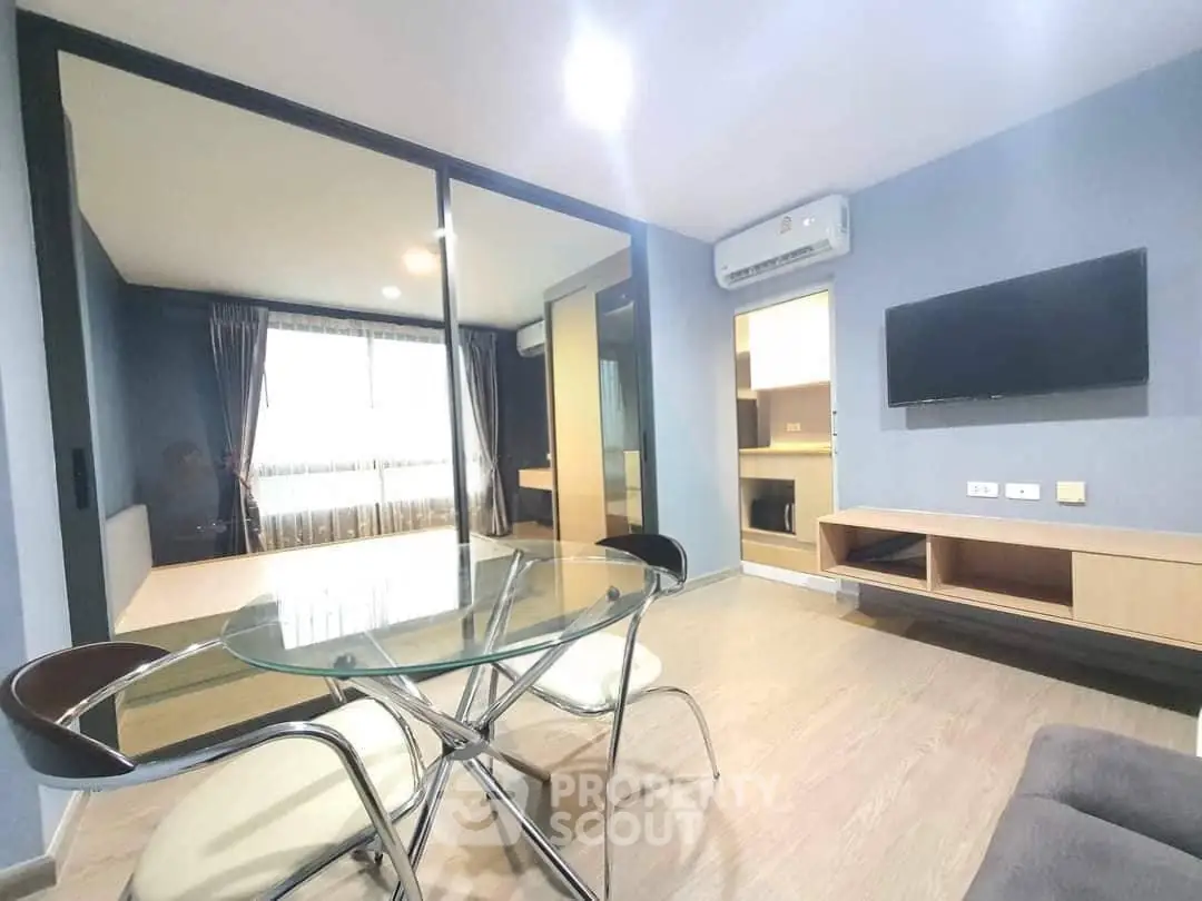 Modern living room with glass dining table and wall-mounted TV in a stylish apartment.