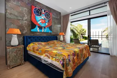 Luxurious bedroom with vibrant decor and poolside view, featuring modern art and elegant furnishings.