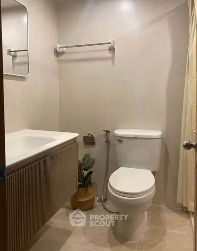 Modern bathroom with sleek fixtures and elegant design, featuring a toilet, sink, and decorative plant.