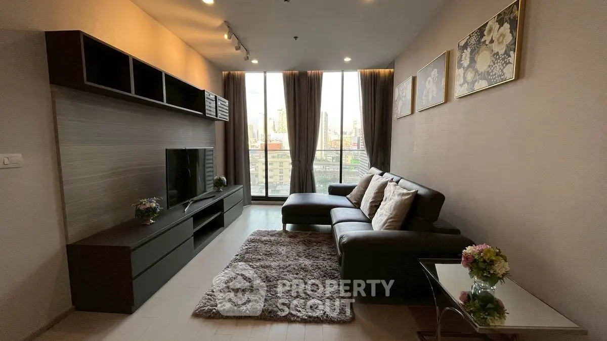 Modern living room with large windows and city view, featuring a cozy sectional sofa and elegant decor.