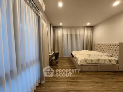 Spacious bedroom with elegant decor and large windows for natural light