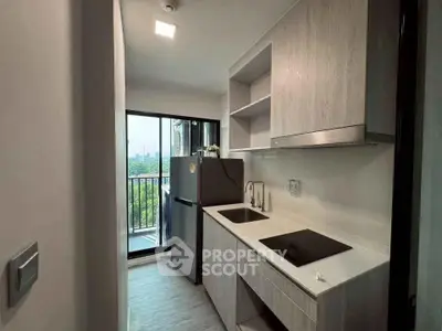 Modern kitchen with sleek cabinetry and balcony view in urban apartment