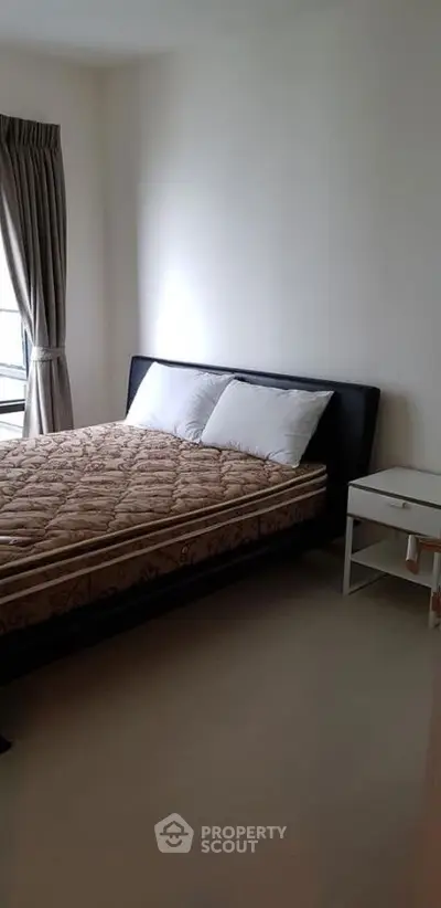 Cozy bedroom with natural light and modern furnishings in a stylish apartment.