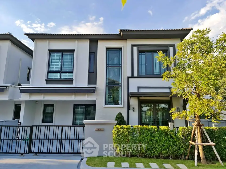 Modern two-story house with large windows and landscaped front yard in a serene neighborhood.