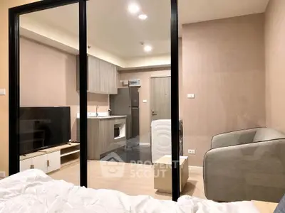 Modern studio apartment with glass partition, cozy living area, and compact kitchen.