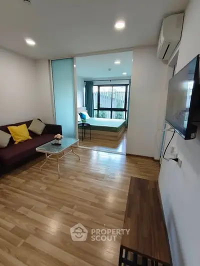 Modern apartment with open living room and bedroom, featuring wooden flooring and stylish decor.