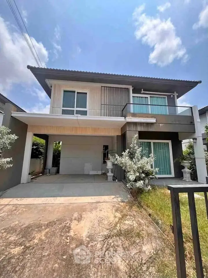 Modern two-story house with spacious driveway and lush greenery under a clear blue sky.