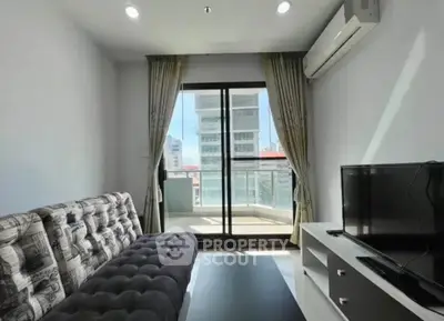 Modern living room with balcony view, featuring stylish sofa and TV setup, perfect for urban living.