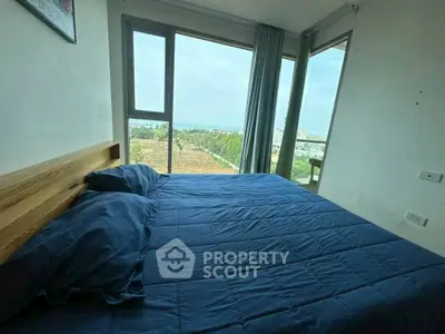 Cozy bedroom with stunning view of lush greenery and distant horizon.