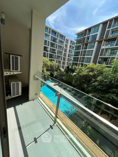 Modern apartment balcony with pool view in a luxurious residential complex.