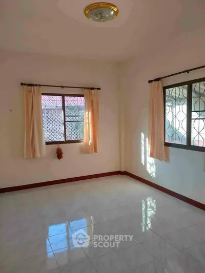 Bright empty room with tiled floor and two windows, ideal for customization.