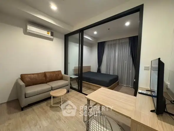 Modern studio apartment with glass partition, cozy living area, and stylish bedroom.