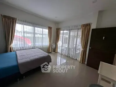 Spacious bedroom with large windows and natural light, featuring modern decor and a serene atmosphere.