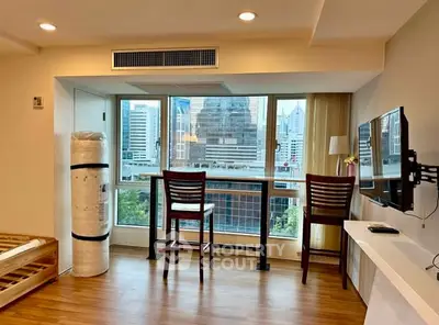 Spacious living room with city view, modern furnishings, and natural light in urban apartment.