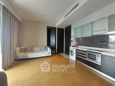 Modern living room with integrated kitchen featuring sleek appliances and cozy seating area.