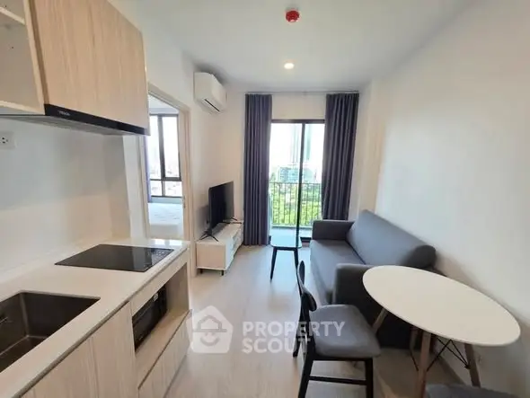 Modern apartment interior with open kitchen and cozy living area, featuring a balcony view.