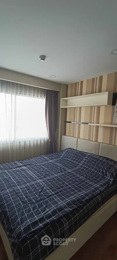Cozy bedroom with stylish decor and ample natural light from large window.