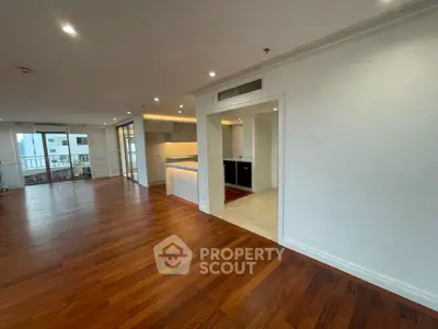 Spacious open-plan living room with hardwood floors and modern kitchen.