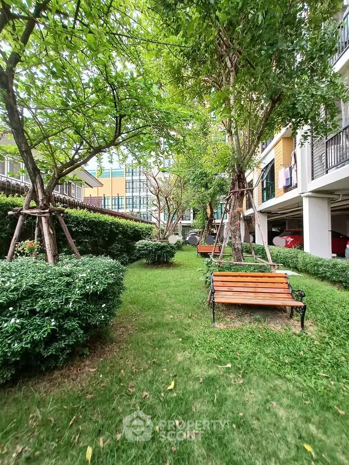 Charming garden area with benches and lush greenery in a residential complex.
