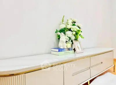 Elegant living room console with decorative flowers and books on a sleek marble top.