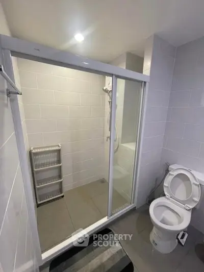 Modern bathroom with glass shower enclosure and sleek tile design.