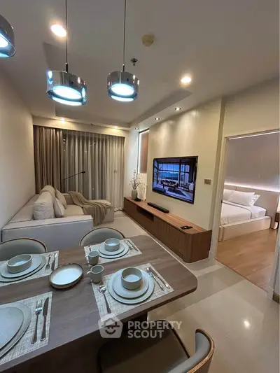Modern living room with dining area and view into a cozy bedroom, featuring elegant lighting and contemporary decor.