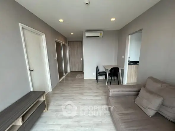 Modern living room with sleek design and neutral tones, featuring a cozy sofa and dining area.