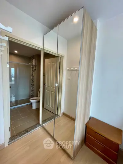 Modern bedroom with mirrored wardrobe and ensuite bathroom in stylish apartment.