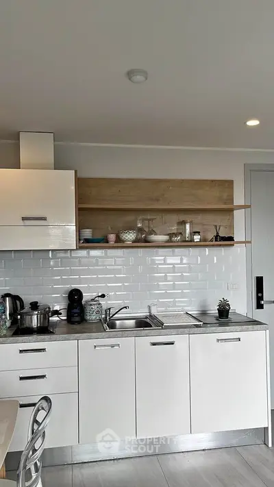 Sleek modern kitchen with white cabinetry, subway tile backsplash, and wooden accents offering a chic culinary space.