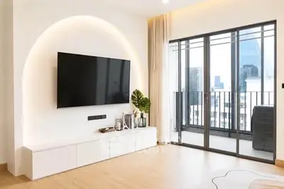 Modern living room with sleek TV setup and large balcony offering city views.