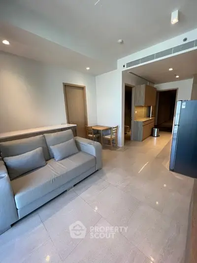 Modern living room with sleek kitchen in open layout, featuring stylish furniture and contemporary design.