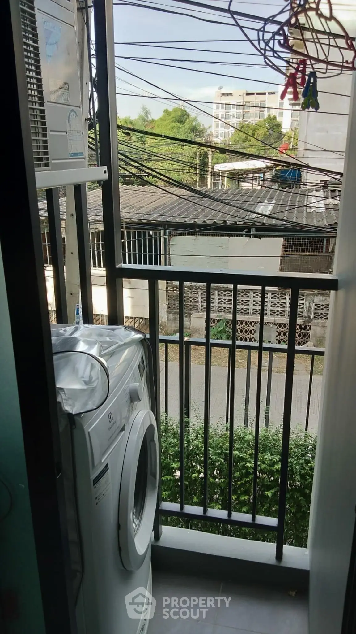 Compact balcony with washing machine and urban view, ideal for city living convenience.