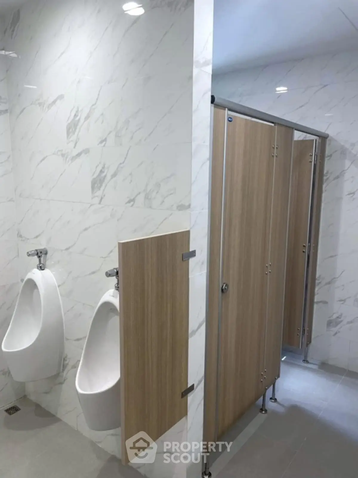 Modern public restroom with marble walls and wooden partitions