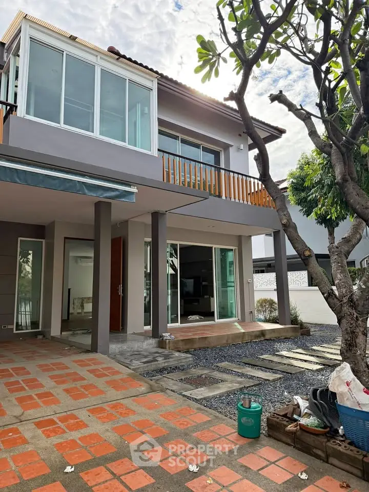 Modern two-story house with large windows and landscaped front yard, perfect for family living.