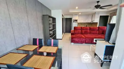 Modern open-layout living room with red sectional sofa, dining area, and sleek kitchen in a contemporary apartment.