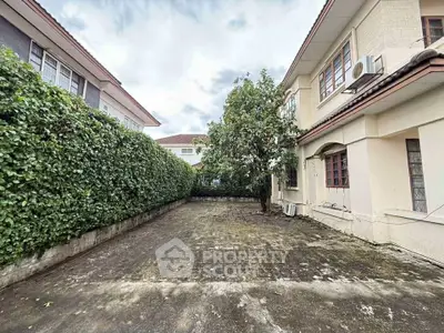 Spacious driveway with lush greenery and elegant two-story house exterior.