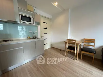 Modern kitchen with sleek cabinetry and dining area in a cozy apartment setting.
