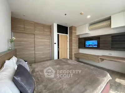 Modern bedroom with built-in wooden wardrobe and wall-mounted TV, featuring sleek design and cozy ambiance.