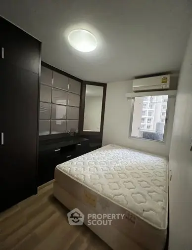 Cozy bedroom with ample natural light, featuring a large bed, built-in wardrobe, and air conditioning unit, perfect for comfortable urban living.