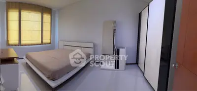 Spacious modern bedroom with sleek furniture and large windows for natural light.