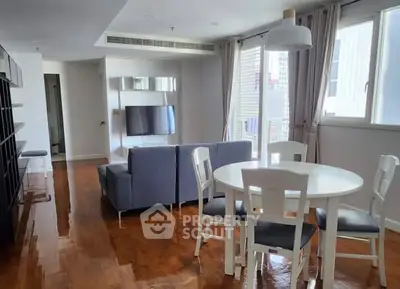 Spacious living room with modern furniture and wooden flooring in a bright apartment.