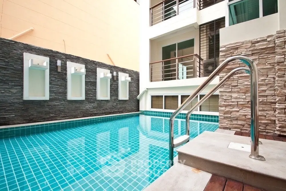 Modern residential building with a stylish swimming pool and elegant stone accents.