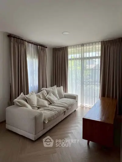 Elegant living room with cozy sofa and large windows offering natural light and serene views.