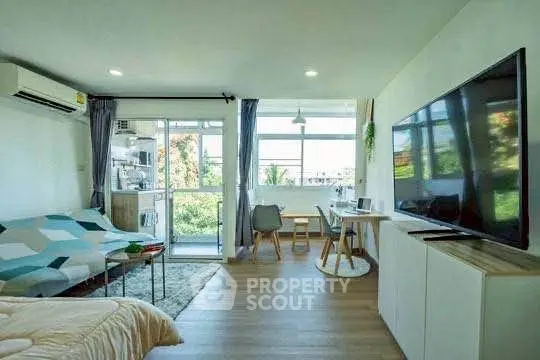 Modern living room with large TV and balcony view, perfect for relaxation.