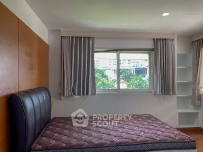 Spacious bedroom with large window and modern design in urban setting.
