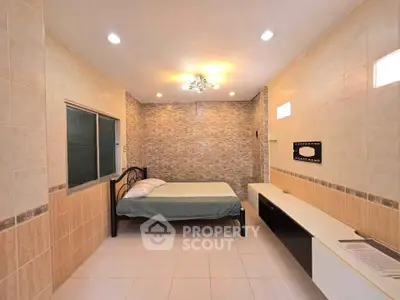Spacious bedroom with modern lighting and tiled walls, featuring a comfortable bed and sleek storage unit.